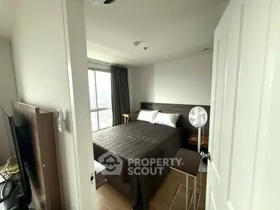 Cozy bedroom with large window and modern furnishings, offering a serene city view.