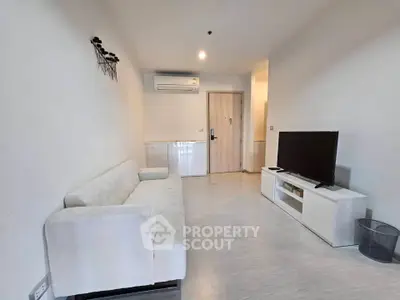 Modern living room with sleek white furniture and wall-mounted air conditioning unit.