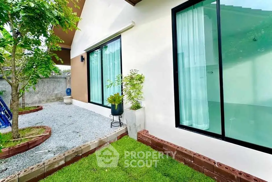 Charming garden view of modern home with large windows and lush greenery.