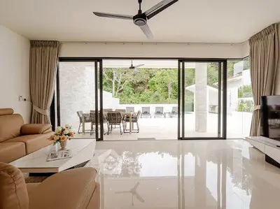Luxurious living room with sliding glass doors opening to a spacious patio and pool area, featuring elegant furnishings.