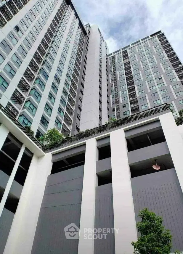 Modern high-rise building exterior with sleek design and lush greenery.