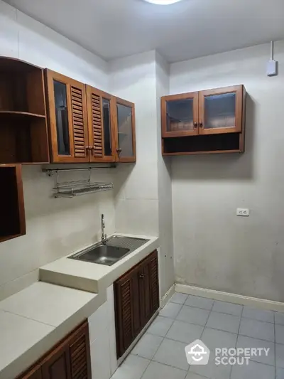 Compact kitchen with wooden cabinets and single sink in a cozy apartment