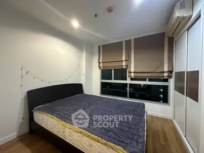 Cozy bedroom with large bed, hardwood floors, and modern air conditioning unit, perfect for restful nights in a city apartment.