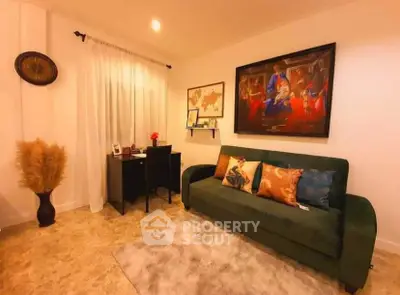 Cozy living room with green sofa, artwork, and small desk setup