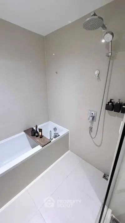 Modern bathroom with sleek bathtub and rainfall showerhead in minimalist design.