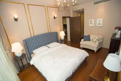 Luxurious bedroom with elegant decor and plush furnishings, featuring a cozy armchair and ambient lighting.