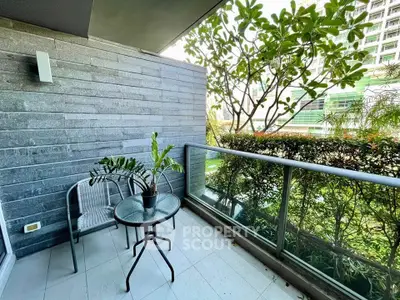 Charming balcony with modern glass railing and lush greenery view, perfect for relaxation.