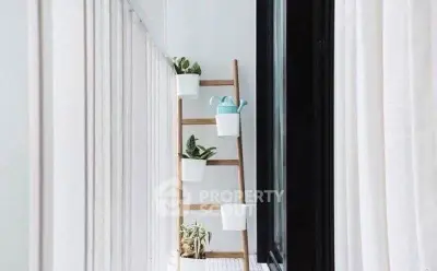 Chic balcony with ladder plant stand and white curtains, perfect for urban gardening.