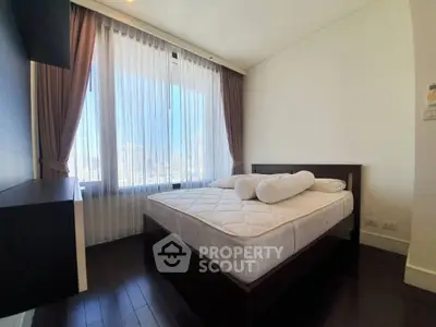 Modern bedroom with large window and city view, featuring elegant curtains and sleek dark wood flooring.