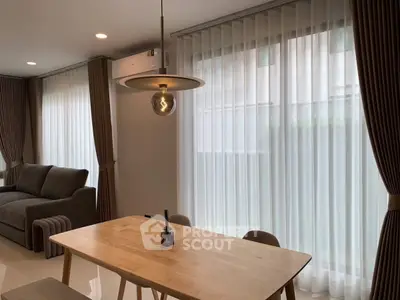 Modern living room with elegant dining area and large windows with sheer curtains.