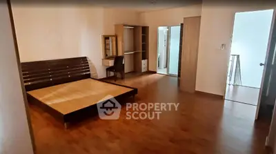 Spacious bedroom with wooden flooring and modern furniture
