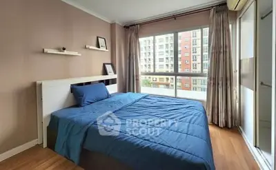 Modern bedroom with large window and blue bedding in urban apartment