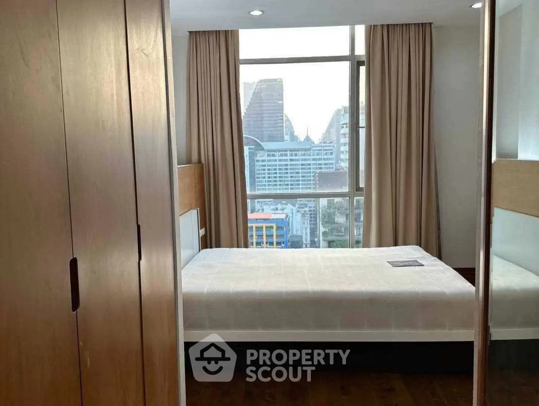 Modern bedroom with city view, featuring large window and sleek furnishings.