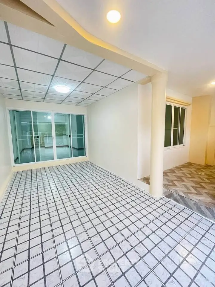 Spacious tiled room with sliding glass doors and modern ceiling lights, perfect for versatile living space.