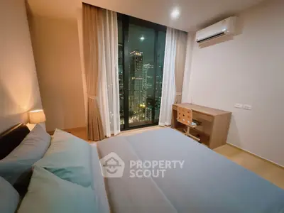 Modern bedroom with city view, featuring a cozy bed and a study desk under soft lighting.