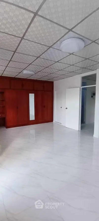 Spacious room with elegant wooden built-in wardrobe and modern ceiling lights.