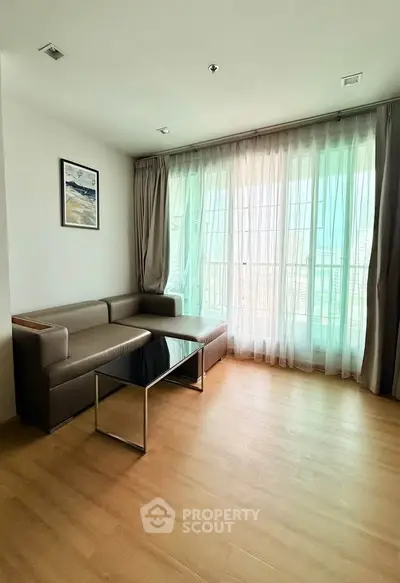 Spacious living room with modern sofa and large windows offering natural light.