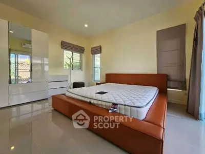 Spacious bedroom with modern furniture and large windows offering natural light.