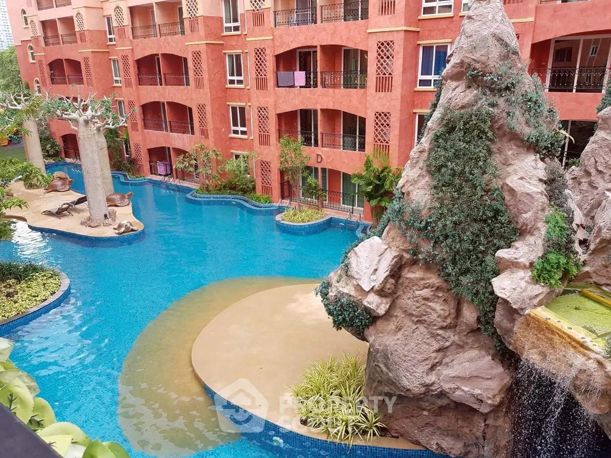 Luxurious apartment complex with stunning pool and rock waterfall feature.