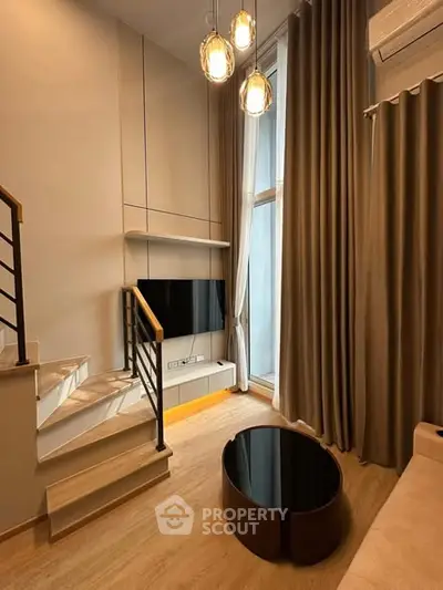 Modern living room with high ceilings, elegant lighting, and stylish staircase