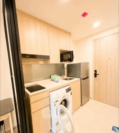 Modern compact kitchen with washing machine and sleek appliances in cozy apartment.
