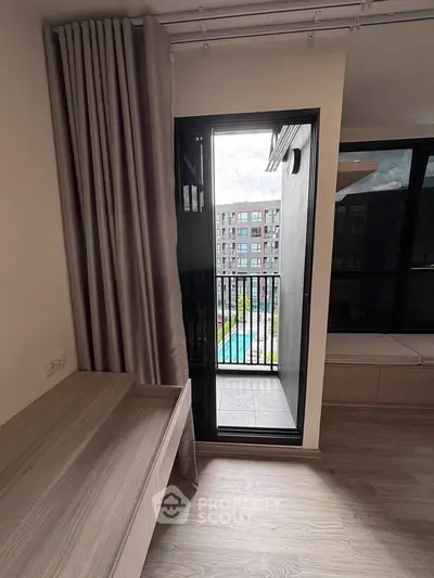 Modern apartment with balcony view overlooking pool and cityscape, featuring sleek interior design.
