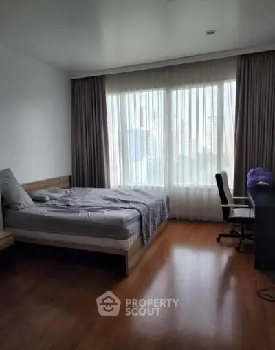 Spacious bedroom with large window and city view, featuring a comfortable bed and study desk.