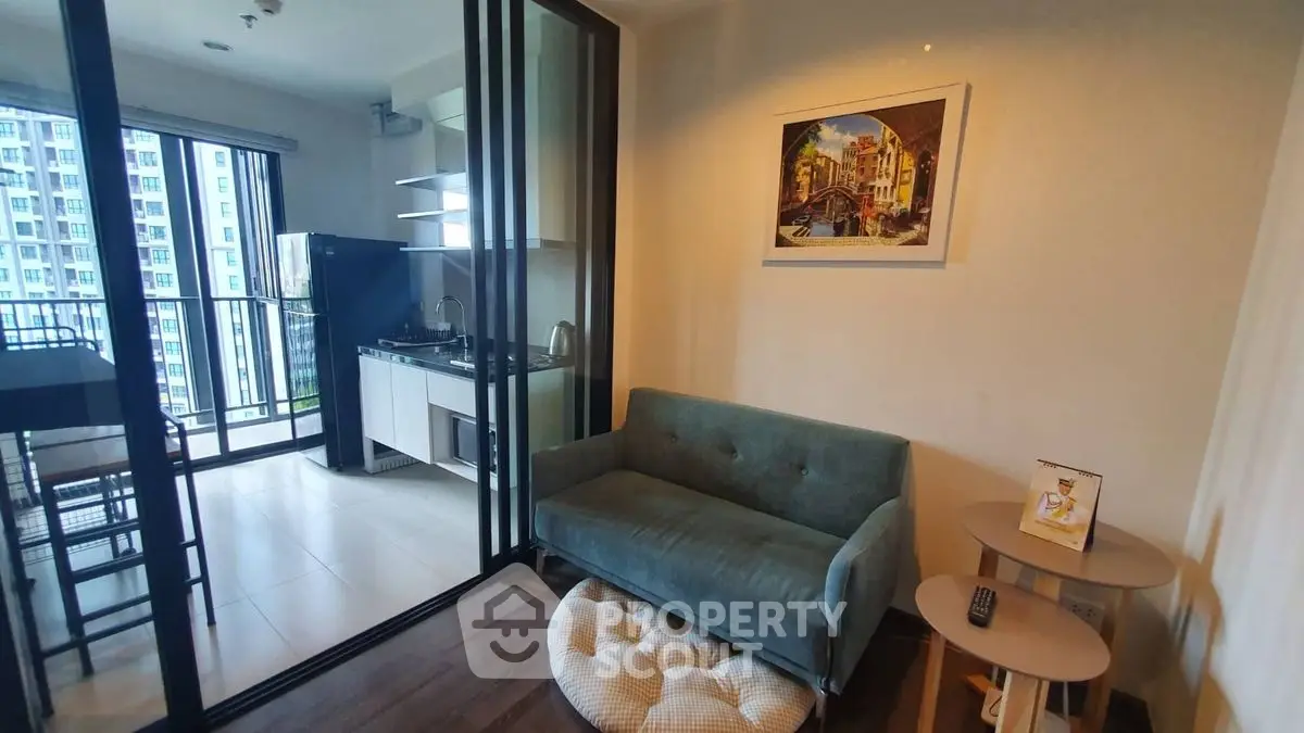 Modern condo interior with cozy living area and compact kitchen, featuring a balcony with city view.