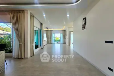 Spacious open-plan living area with large windows and garden view, perfect for modern living.