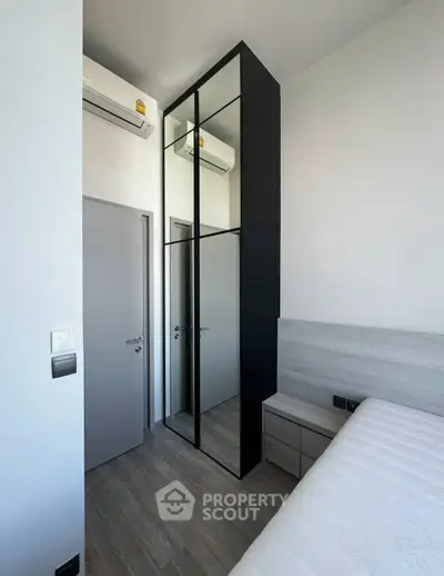 Modern bedroom with sleek mirrored wardrobe and air conditioning unit