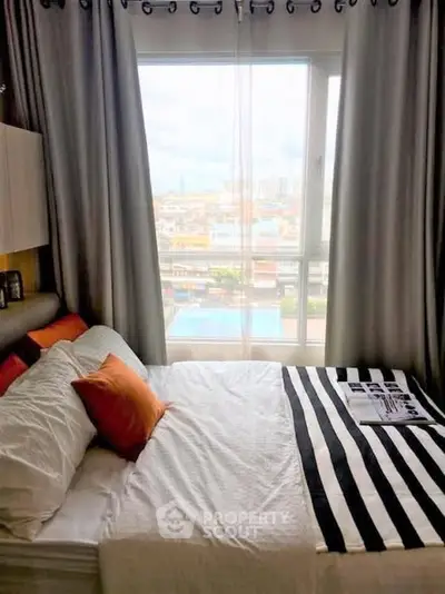 Cozy bedroom with large window offering a stunning city view, featuring modern decor and comfortable bedding.