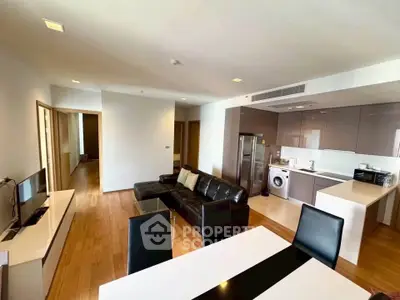 Spacious modern living room with open kitchen and sleek furnishings in a contemporary apartment.