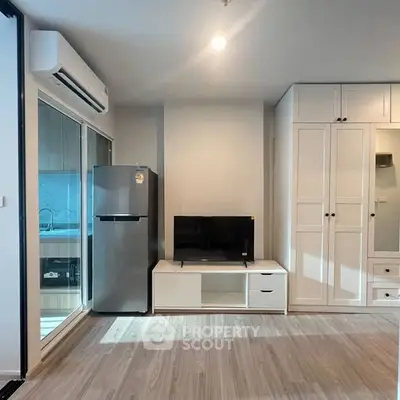 Modern living room with sleek design, featuring a TV, fridge, and ample storage space.