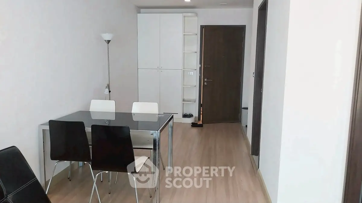 Modern dining area with sleek table and chairs, wooden flooring, and minimalist decor.