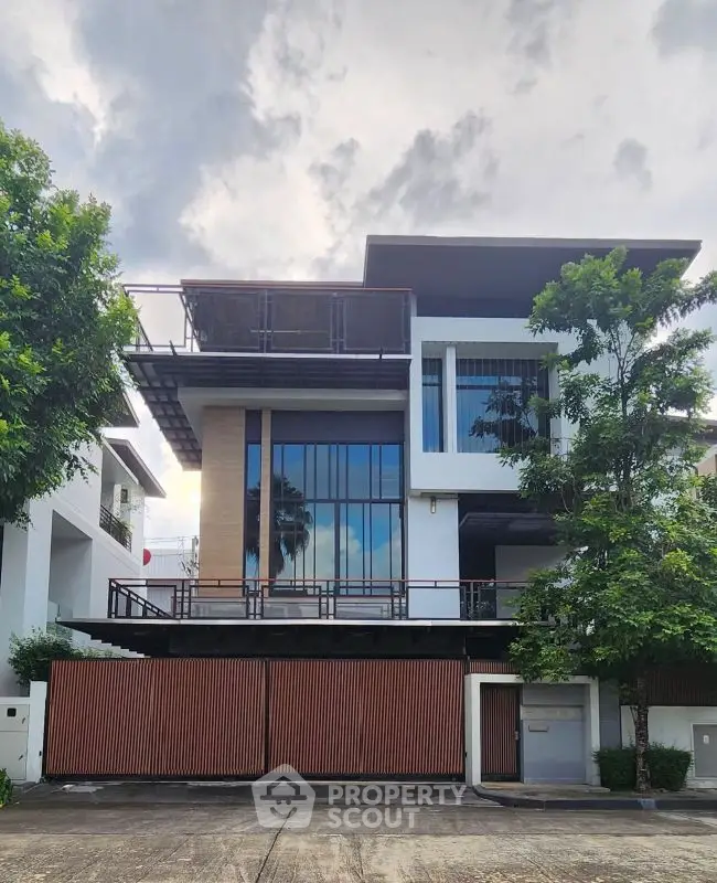 Modern three-story house with large windows and sleek design in a suburban neighborhood.