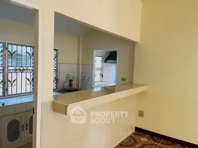 Charming open-layout kitchen with tiled countertops and decorative window grills.
