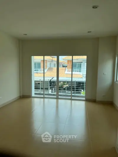 Spacious living room with large windows offering a view of neighboring houses.