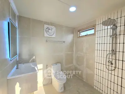 Modern bathroom with sleek fixtures and natural light, featuring a spacious shower and elegant tile design.