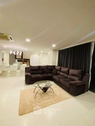 Spacious modern living room with elegant sectional sofa and stylish glass coffee table, perfect for entertaining.