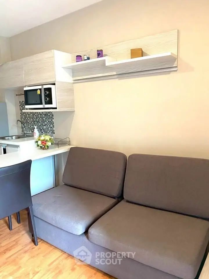 Modern living room with sleek kitchen and cozy sofa, ideal for urban living.