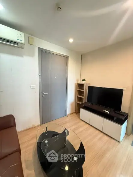 Modern living room with sleek furniture and TV setup, featuring wooden flooring and neutral tones.