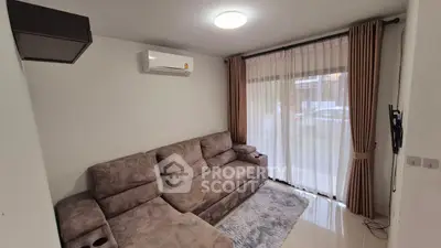 Cozy living room with plush sofa and large window draped with curtains