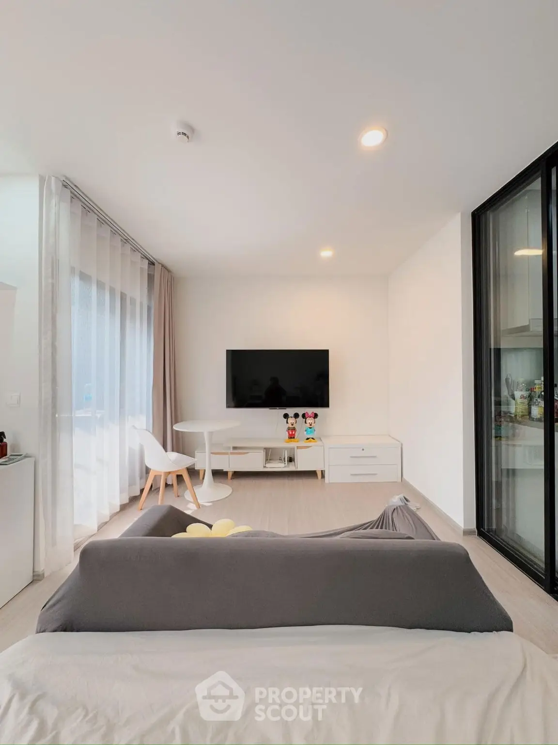 Modern living room with sleek furniture and wall-mounted TV, featuring a cozy ambiance and natural light.