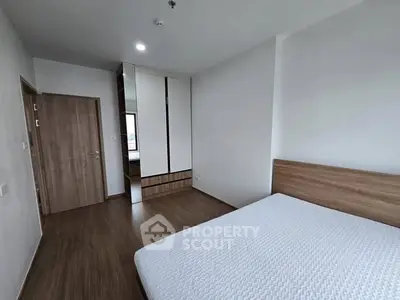 Spacious modern bedroom with wooden flooring and built-in wardrobe