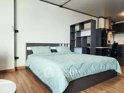 Modern bedroom with stylish bed and open kitchen layout in a contemporary apartment.