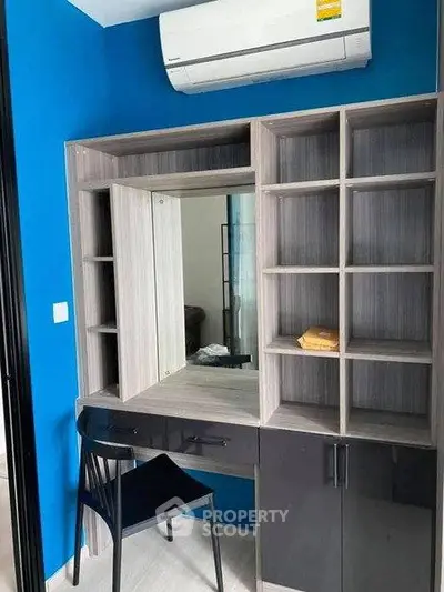Modern study nook with built-in shelves and air conditioning in a vibrant blue room.