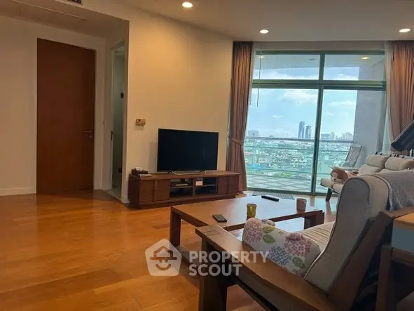 Spacious living room with wooden flooring and city view balcony in modern apartment.