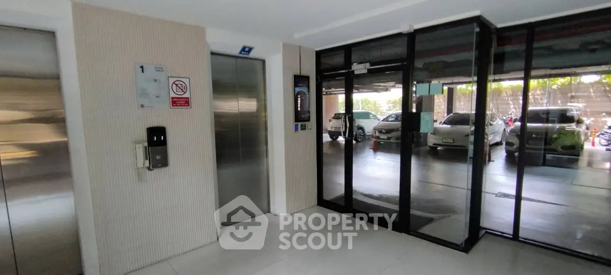Modern building entrance with elevator and parking view, showcasing sleek design and convenience.