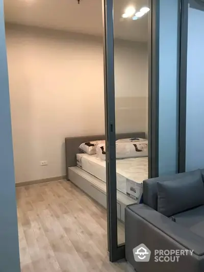 Modern compact bedroom with glass partition and cozy sofa in stylish apartment