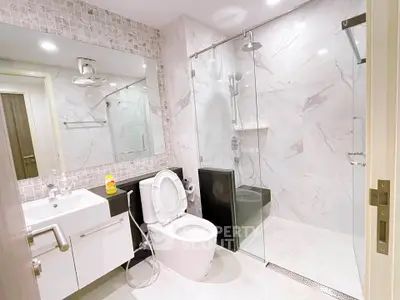 Modern bathroom with sleek design, featuring a glass-enclosed shower and stylish fixtures.